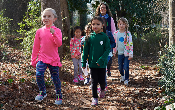 group of young girl scouts and volunteer walking outside